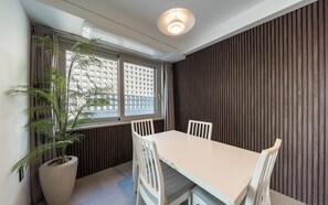 Un comedor con una mesa, sillas, una planta en maceta y una ventana con persianas.