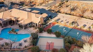 Una proprietà residenziale con piscina, campo da tennis e giardino curato.