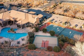 Ein Wohnhaus mit Swimmingpool, Tennisplatz und einem angelegten Garten.