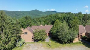 A residential area with multiple houses surrounded by dense forest and a mountain in the background. - The Back Nine | Golf, Mount Snow, & Vermont Escape (Wilmington)