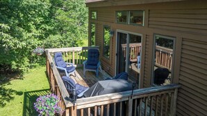 A deck with outdoor furniture, a covered seating area, and a view of the surrounding greenery. - The Back Nine | Golf, Mount Snow, & Vermont Escape (Wilmington)