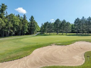 A golf course with a sand bunker, trees, and a clear sky. - The Back Nine | Golf, Mount Snow, & Vermont Escape (Wilmington)