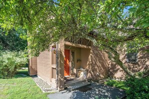 A small wooden structure with a porch, a red door, and a small table. - The Back Nine | Golf, Mount Snow, & Vermont Escape (Wilmington)