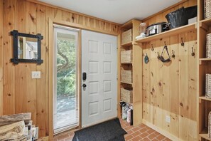 A wooden interior with a sliding door, shelves with baskets, and a black mat at the entrance. - The Back Nine | Golf, Mount Snow, & Vermont Escape (Wilmington)
