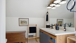 A bathroom with a wooden vanity, a sink with a mirror, and a towel rack. - The Back Nine | Golf, Mount Snow, & Vermont Escape (Wilmington)