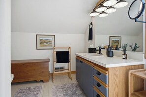 Ein Badezimmer mit einem Holzkosmetikschrank, einem Waschbecken mit Spiegel und einem Handtuchhalter.