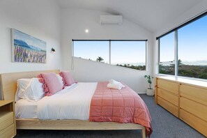 A modern bedroom with a large bed, a view of the outdoors, and a painting on the wall.