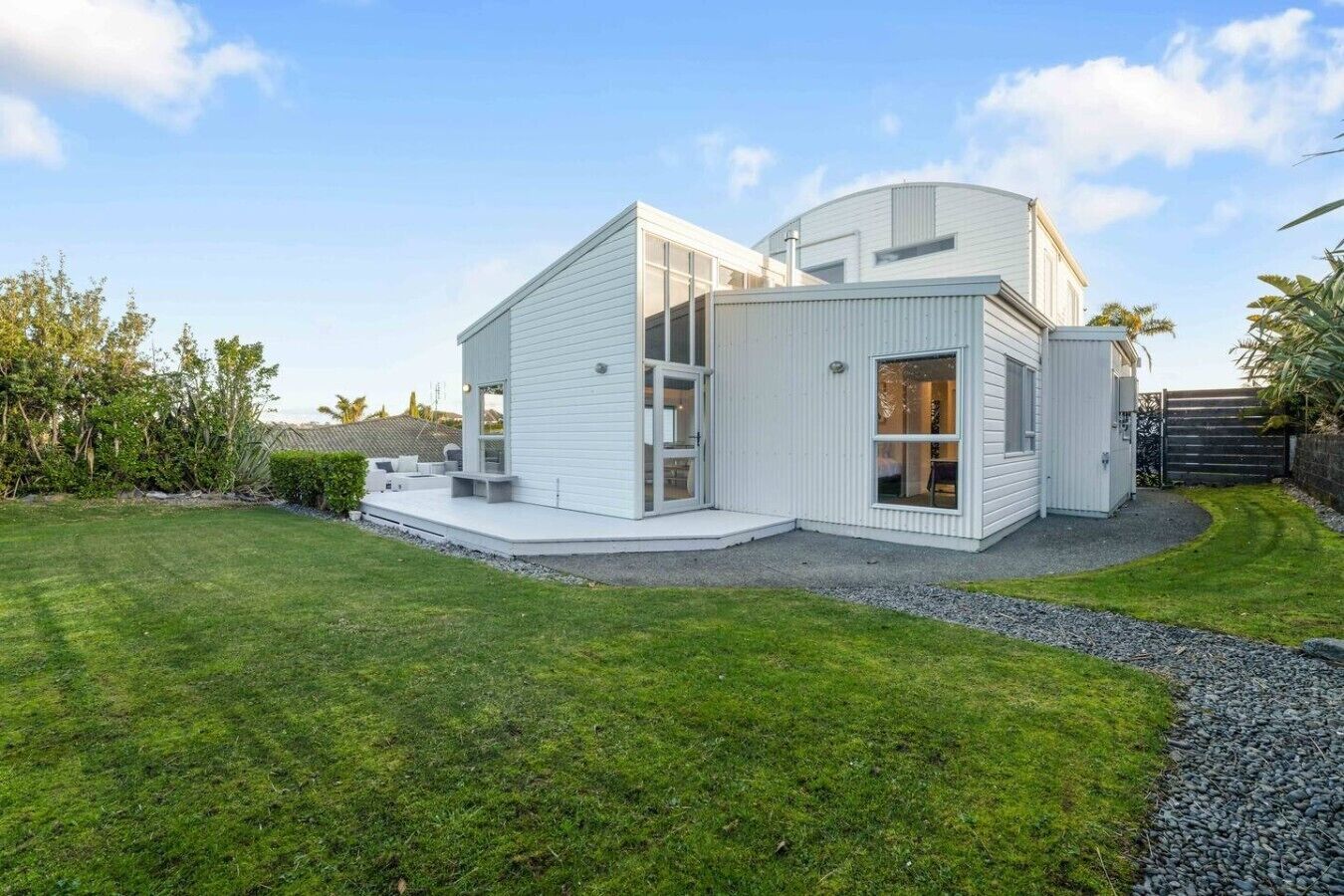 A modern two-story house with a flat roof, large windows, and a well-maintained lawn.