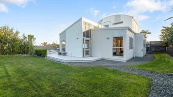 A modern two-story house with a flat roof, large windows, and a well-maintained lawn.