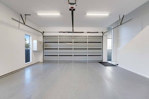 Eine geräumige, leere Garage mit einer großen, geschlossenen Garagentür, Neonbeleuchtung und einem sauberen Betonboden.