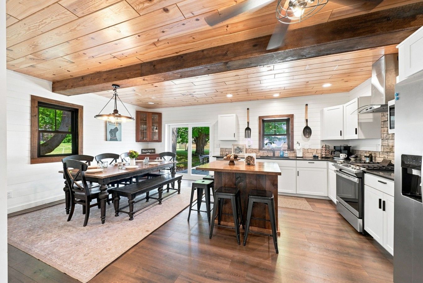 A modern kitchen with wooden beams, white cabinetry, and a central island.