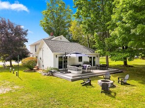 Una casa de una planta con un patio, muebles de exterior y un pequeño jardín.