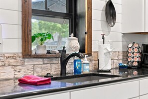 Eine Küche mit einem schwarzen Wasserhahn, einem Fenster mit Blick und einem Geschirrgestell mit Tellern.