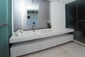 Une salle de bain moderne avec un grand miroir, un plan de toilette blanc et un lavabo intégré.