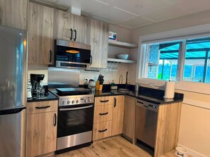 A modern kitchen with stainless steel appliances, wooden cabinetry, and a window providing a view. - Zen on the Lake Spa | Mission, BC (Mission)