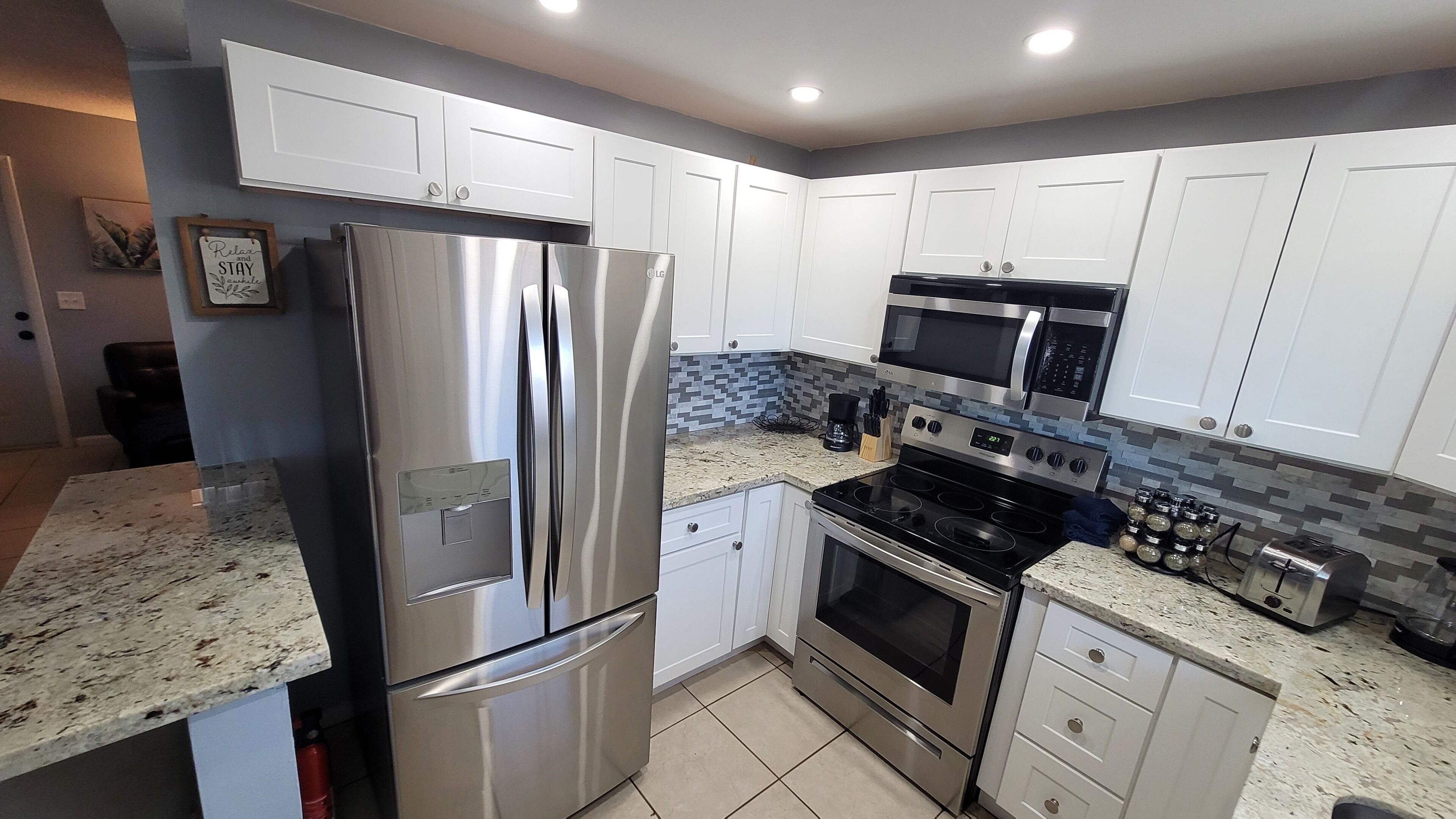 Una cocina moderna con electrodomésticos de acero inoxidable, armarios blancos y una salpicadera de azulejos.