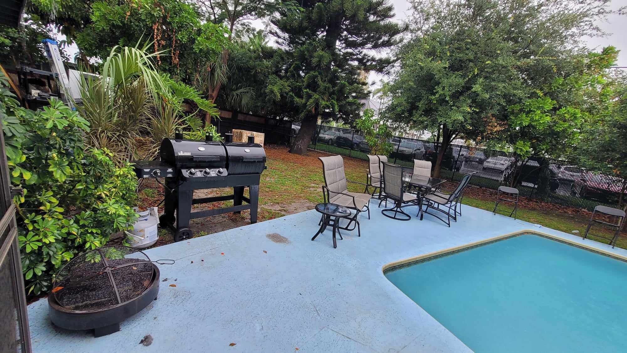 Um quintal com piscina, churrasqueira e mobiliário de jardim.