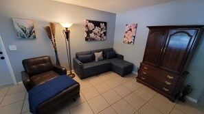 A living room with a sofa, a chair, a floor lamp, and a cabinet. - You'll love it here (Palm Beach Gardens)