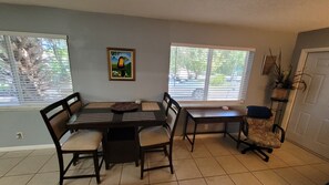 A dining area with a table, chairs, a painting, and windows with blinds. - You'll love it here (Palm Beach Gardens)