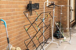 A laundry area with a metal rack for hanging clothes, a hose reel, and a vacuum cleaner. - Relaxing 4BR Wantirna Home | Everything You Need (Wantirna South)