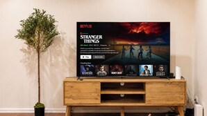 Een televisie toont de Netflix-serie 'Stranger Things' met een houten tv-meubel eronder.