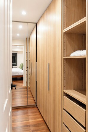 A hallway with wooden wardrobes, a bed, and a shelf with a fluffy white item. - Wantirna 4BR Family Home | Space for Longer Stays (Wantirna South)