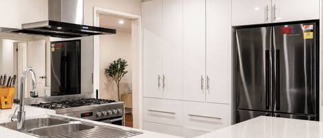 A modern kitchen with stainless steel appliances, a gas stove, and white cabinetry.