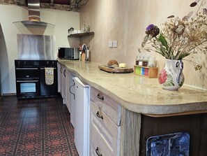 Eine Küche mit Einbauofen, Mikrowelle und einer Holzausziehtischplatte mit einer Vase getrockneter Blumen.