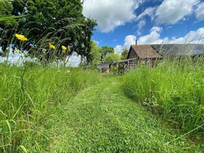Ein ländlicher Pfad führt zu einem traditionellen Backsteinhaus mit Garten.