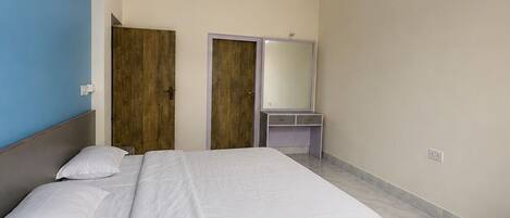 Un dormitorio con cama, ventilador de techo, armario, espejo y puerta.