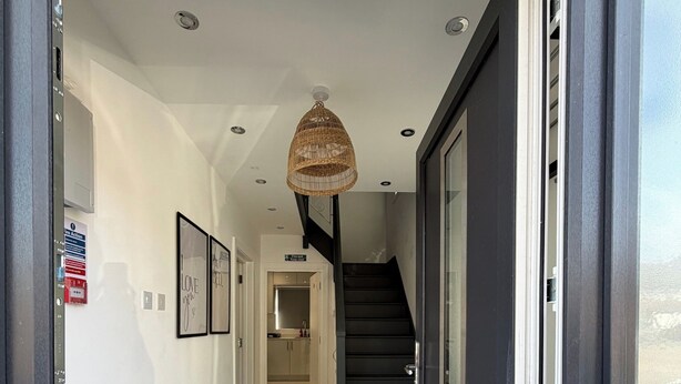 A modern hallway with a staircase leading to a kitchen area. - House Sleeps 9 with Wifi (Slough)
