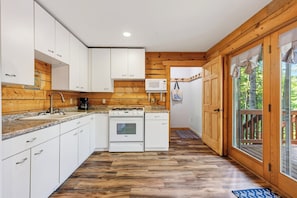Una cocina moderna con armarios blancos, una estufa y un microondas.