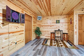 A wooden interior with a dartboard, a clock, a sign, a plant, and a bar area. - Hummingbird Grove - A Private Escape (Birchwood)