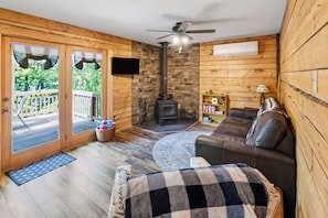 A cozy living room with a fireplace, a sofa, and a television. - Hummingbird Grove - A Private Escape (Birchwood)