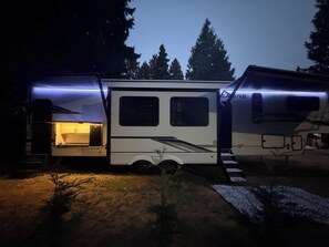 En hvid autocamper med et køkken, et soveområde og et badeværelse.