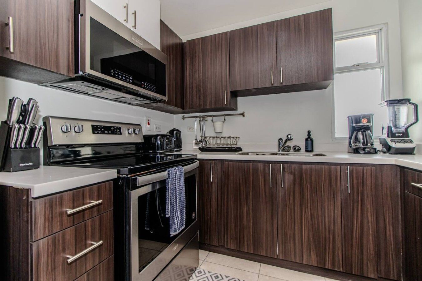 Een moderne keuken met donkerhouten kasten, roestvrijstalen apparatuur en een ingebouwde oven.