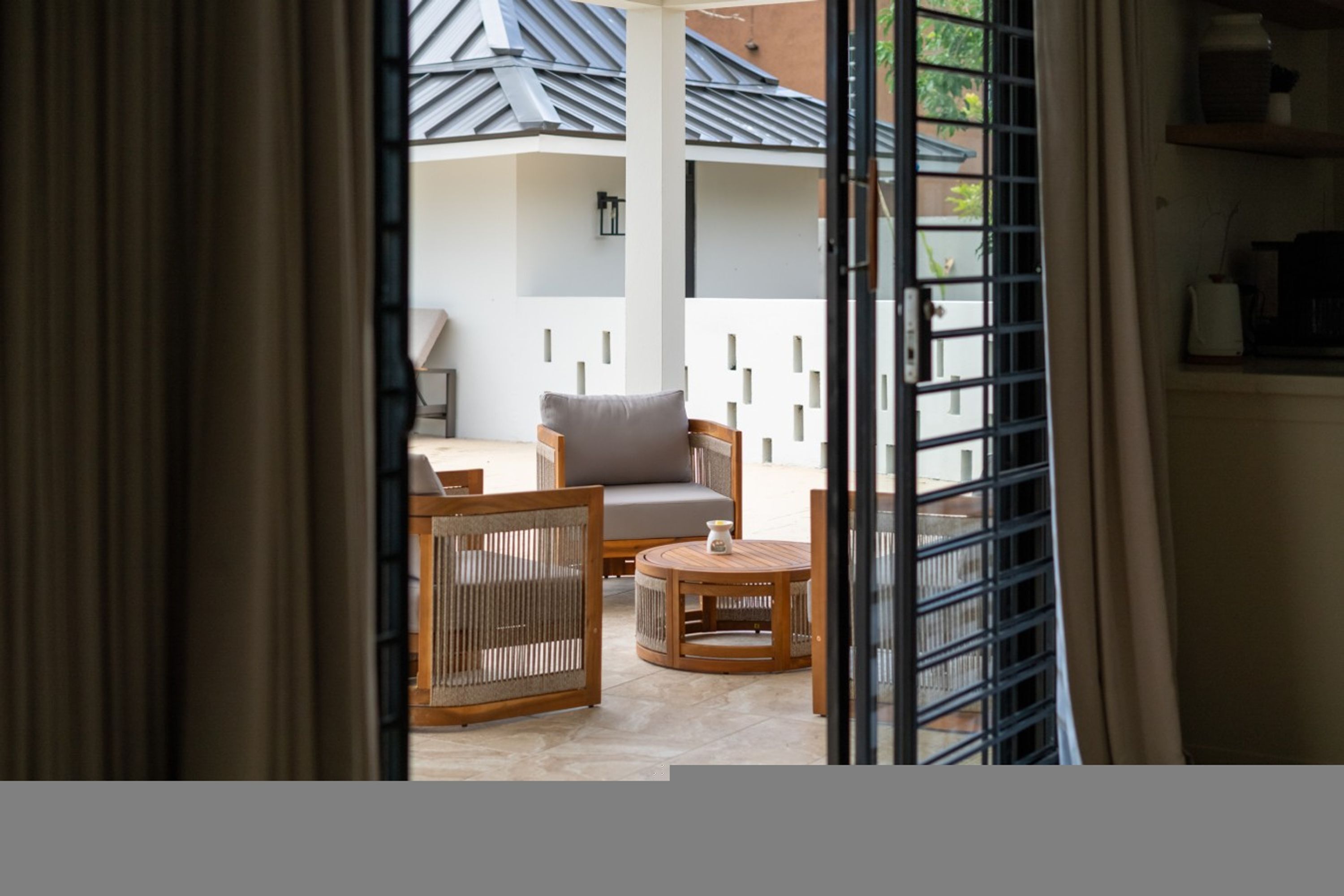 A room with a sofa, a chair, and a small table. There is a window with blinds.