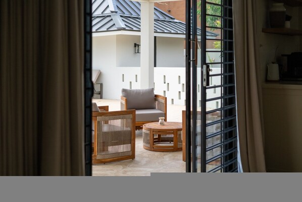 A room with a sofa, a chair, and a small table. There is a window with blinds.