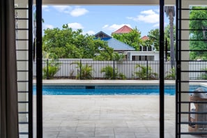 A swimming pool with a tiled deck, surrounded by a fence and greenery. - 5BR Luxe Retreat in Runaway Bay Private Pool Beach Access (Runaway Bay)