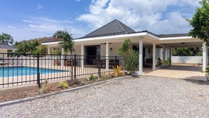 A modern house with a covered patio, a swimming pool, and a gravel driveway. - 5BR Luxe Retreat in Runaway Bay Private Pool Beach Access (Runaway Bay)
