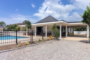 A modern house with a covered patio, a swimming pool, and a gravel driveway. - 5BR Luxe Retreat in Runaway Bay Private Pool Beach Access (Runaway Bay)