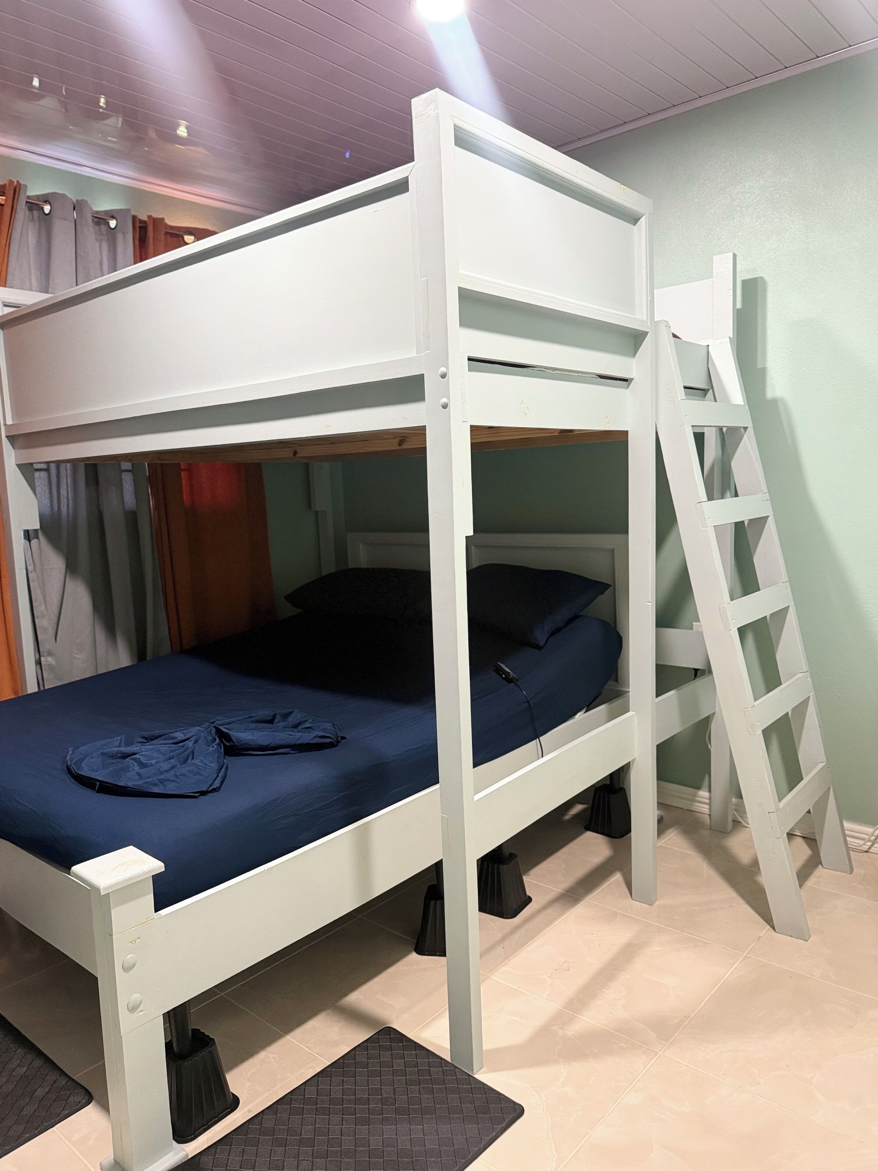 A bunk bed with a ladder, a desk, and a chair.