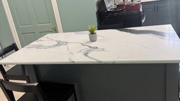 A kitchen with a marble countertop island, a small potted plant, and a stove.