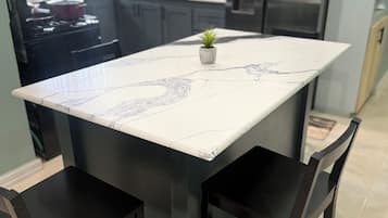 A kitchen with a central island, dark chairs, and a potted plant.