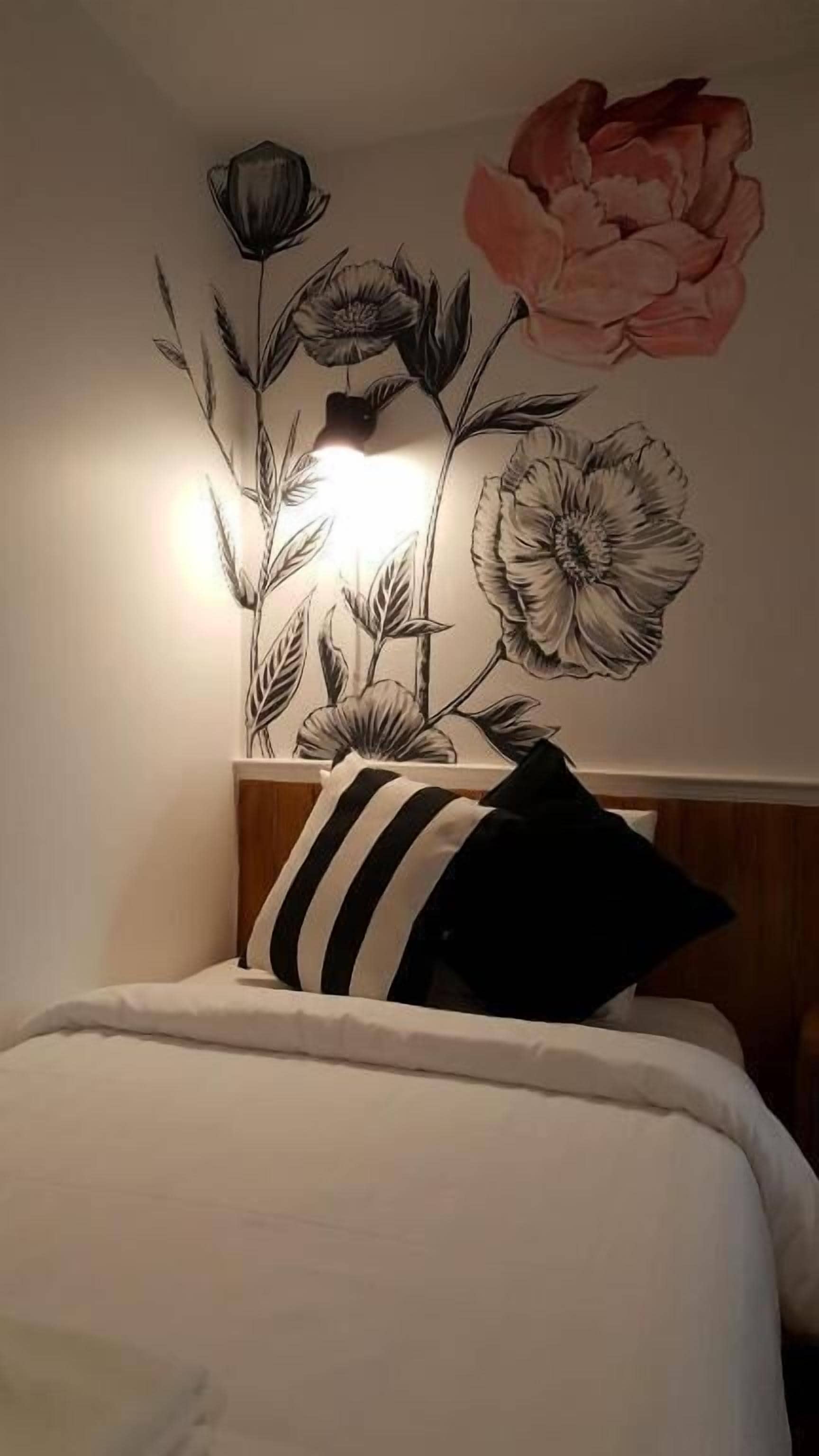 A bedroom with a bed, a pillow, and a wall mural of flowers.