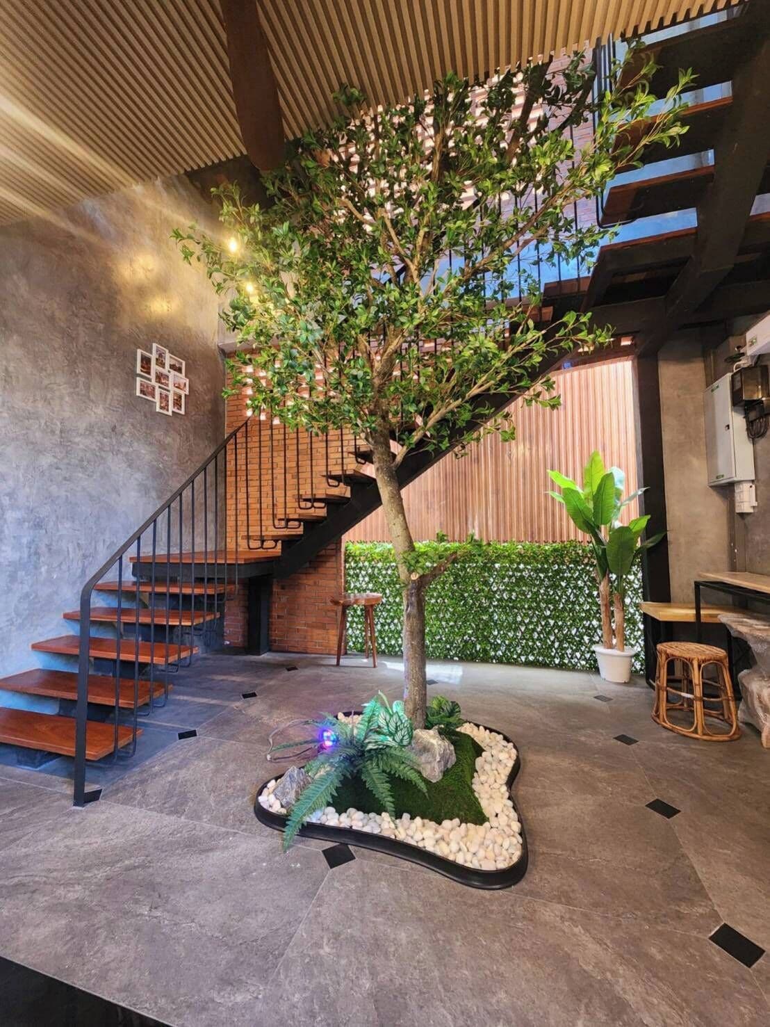 A staircase with a tree planter in the center, a seating area with a table and chairs, and a wall with a geometric pattern.