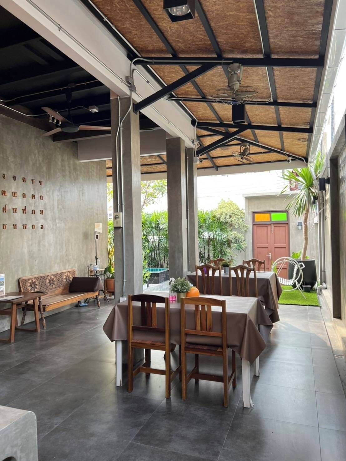 A spacious indoor area with a high ceiling, concrete walls, and a mix of wooden and metal furniture.