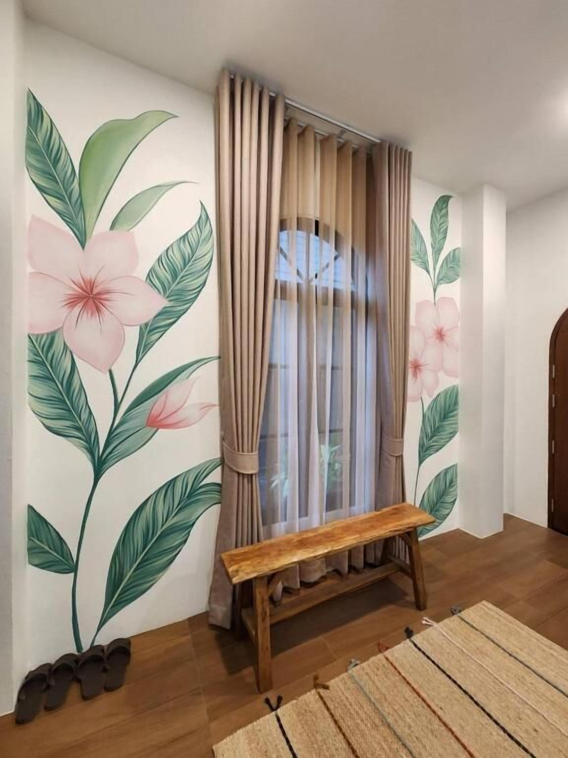 A room with a wooden bench, beige curtains, and a wall with a floral mural.