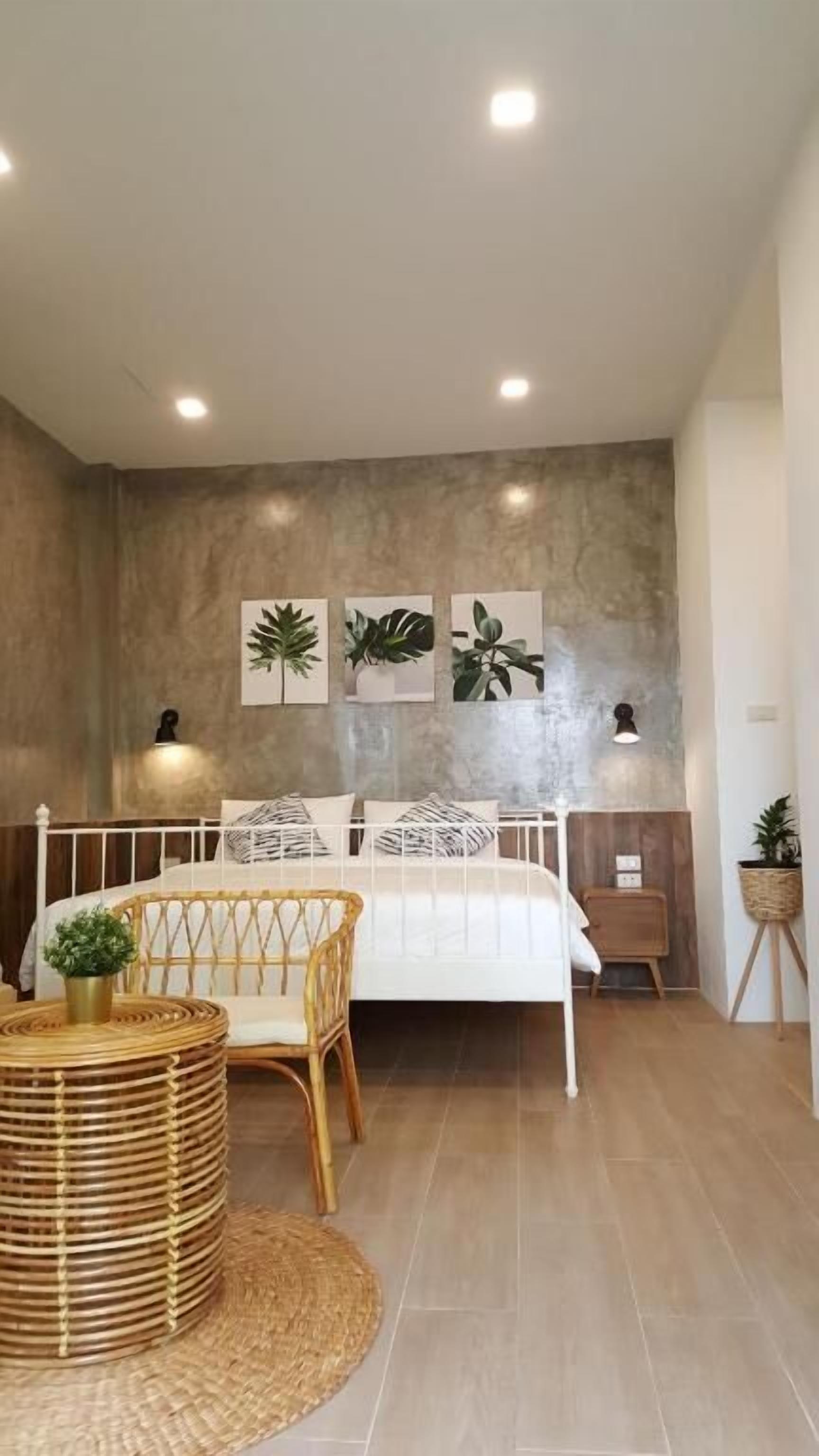 Quarto com cama, mesa de cabeceira, luminária e arte nas paredes.