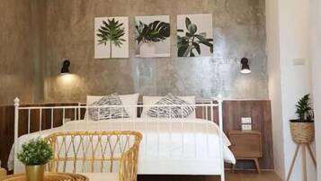 Quarto com cama, mesa de cabeceira, luminária e arte nas paredes.